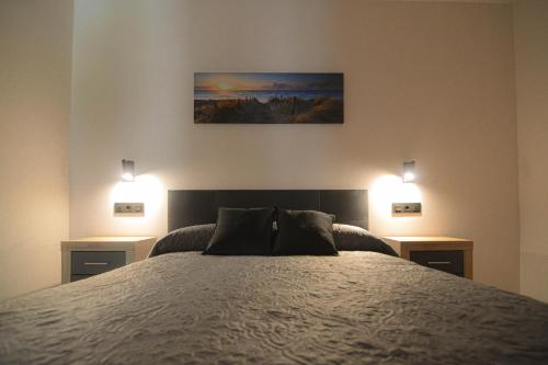 Apartamentos Fuente La Pipa في أفين: غرفة نوم بسرير كبير مع مواقف ليلتين
