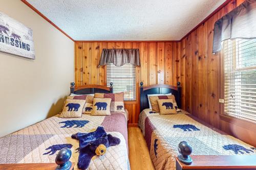 two beds in a room with wooden walls and wooden floors at Bear Crossing in New Tazewell