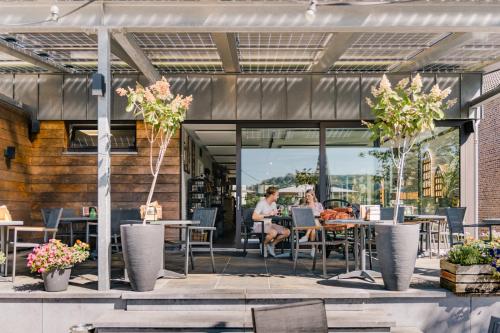 a patio with tables and chairs and people sitting at tables at B&B Brasserie Villare in Wijlre