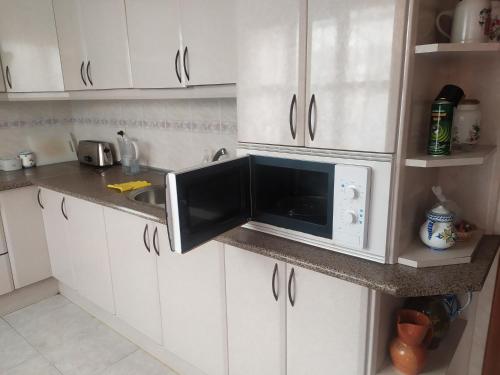a kitchen with white cabinets and a microwave on a counter at Habitacion Privada Familiar Toledo in Toledo
