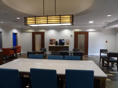 a waiting room with tables and blue chairs at Holiday Inn Express & Suites - Huntsville Airport by IHG in Madison