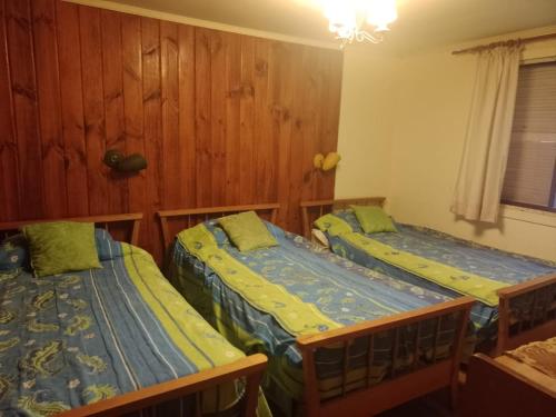 two beds in a room with wood paneling at Pichidangui vista al Mar 8 camas in Los Vilos