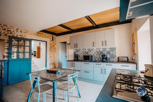 eine Küche mit blauen Schränken und einem Tisch mit Stühlen in der Unterkunft Agréable maison de village avec terrasse in Pougnadoresse