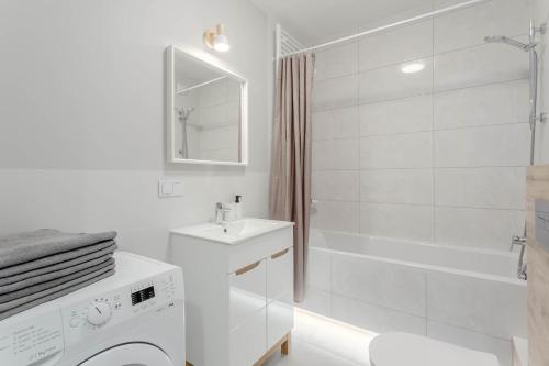a white bathroom with a sink and a tub at Enjoy! Ursus in Warsaw