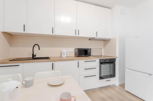 a white kitchen with white cabinets and a sink at Enjoy! Ursus in Warsaw