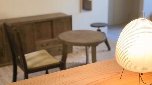 a room with a table and chairs and a table and a lamp at Nisainoyuyado Asahiya in Beppu