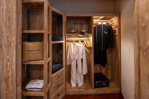 a walk in closet with wooden cabinets and clothes at Keliki Luxury Lodge in Ubud