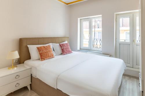 - une chambre blanche avec un lit et 2 fenêtres dans l'établissement Cozy Flat w Balcony 8 min to Metro and Taksim, à Istanbul