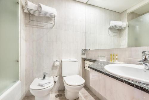a white bathroom with a toilet and a sink at Eurostars Atlántico in A Coruña