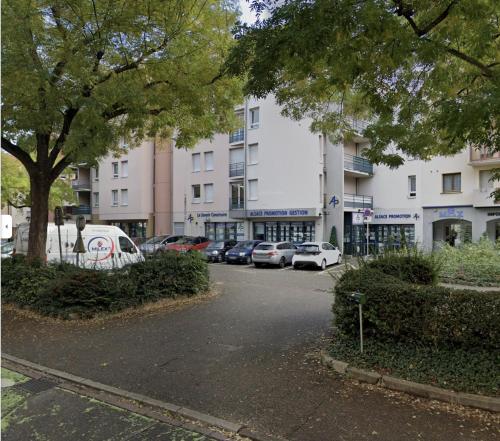 a parking lot with cars parked in front of a building at LE MUSCAT in Colmar