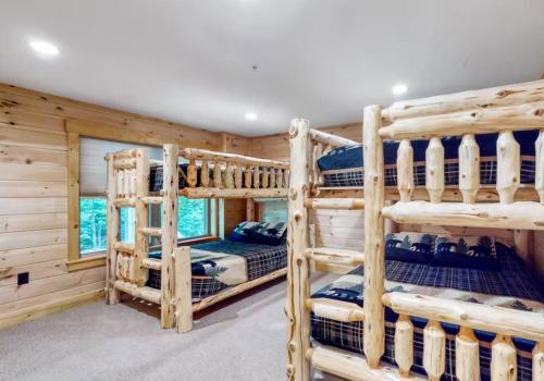 a log cabin bedroom with three bunk beds at Kingslanding Cabin in Carrabassett