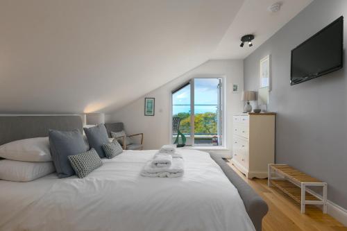 1 dormitorio con 1 cama blanca grande y TV en la pared en 7 Sandy Lane, en St Ives