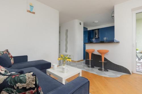 a living room with two blue couches and a kitchen at Comfy Apartment Powstańców Śląskich by Renters in Warsaw