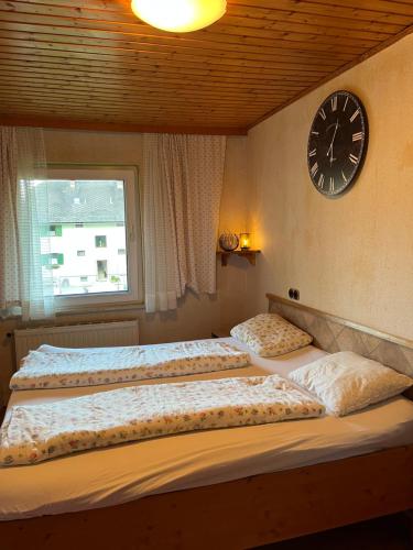 two beds in a bedroom with a clock on the wall at Naturparadies Nähe Grüner See in Oberdorf