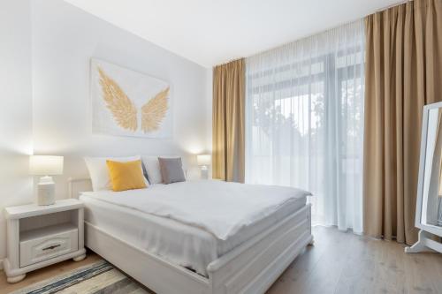 a white bedroom with a large bed and a window at Petofi Flat in Oradea