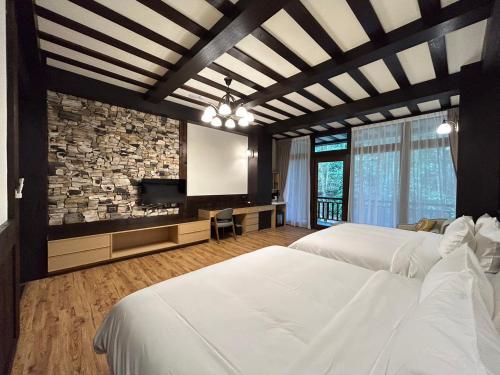 a bedroom with two white beds and a stone wall at 日月潭森堡萊夫莊園 in Yuchi