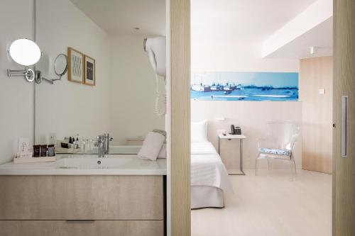 a bathroom with a sink and a bed in a room at ALEGRIA Mar Mediterrania - Adults Only 4*Sup in Santa Susanna