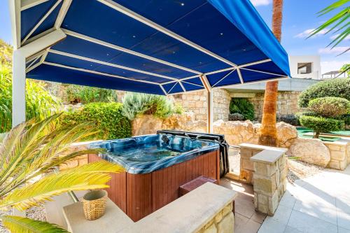 a hot tub under a blue umbrella on a patio at The Bridge Villa by Ezoria Villas in Coral Bay