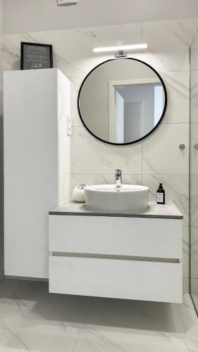 a white bathroom with a sink and a mirror at Linden Apartman 104 - Adults Only in Mosonmagyaróvár