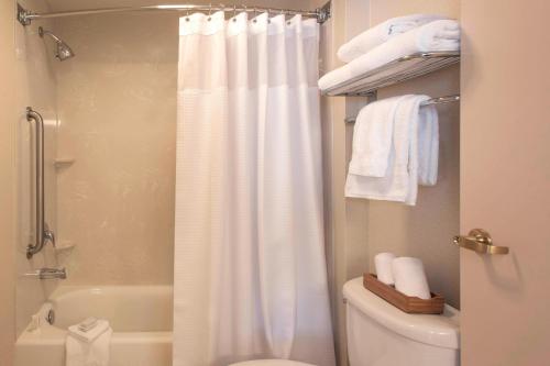 a bathroom with a white shower curtain and a toilet at SpringHill Suites by Marriott Charlotte Airport in Charlotte