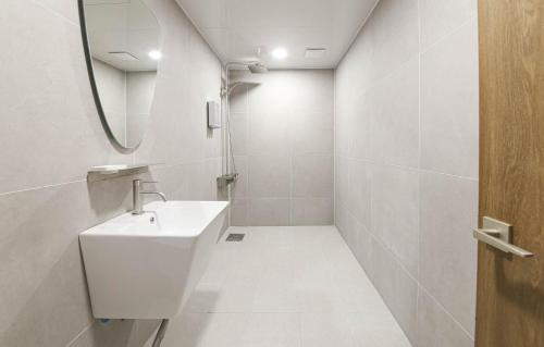 Baño blanco con lavabo y espejo en Brown Dot Hotel Sinan, en Gwangju
