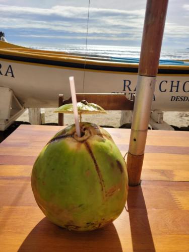 伊塔佩馬的住宿－Apartamento vista mar com 3 quartos e churrasqueira，坐在船边桌子上的椰子