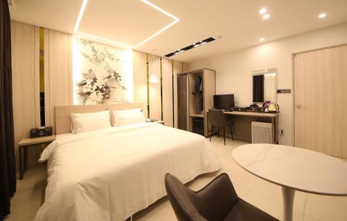 a bedroom with a bed and a table and a desk at Brown Dot Hotel Sinan in Gwangju