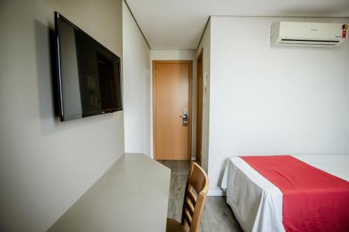 Habitación pequeña con cama y TV. en Lagoa Flat Hotel, en Lagoa da Prata