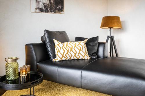 a black leather couch in a living room with a lamp at Boutiquehotel Genusswerk Eifel in Körperich