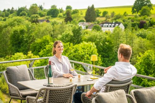 a man and a woman sitting at a table on a balcony at Boutiquehotel Genusswerk Eifel in Körperich