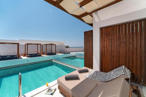 a swimming pool with a lounge chair next to a house at THERETRA PEFKI Seaside in Pefki Rhodes