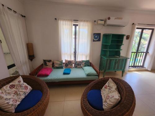 sala de estar con 2 sillas de mimbre y sofá en Riviera Hermitage Goa, en Arpora
