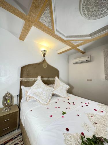 a bedroom with a white bed with roses on it at Dar Khmissa Fes-Luxury Stay Fes Medina in Fès