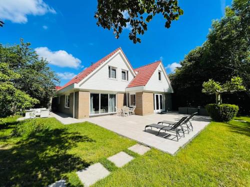 een wit huis met een rood dak en een patio bij VILLA CALMA Rust Ruimte Luxe inclusief private jacuzzi in Zeewolde