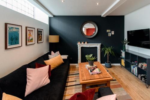 a living room with a black couch and a table at Unique, stylish and secluded home, with parking in the heart of historic York in York