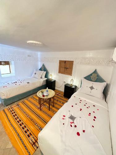 um quarto com duas camas e uma mesa num quarto em Dar Khmissa Fes em Fez