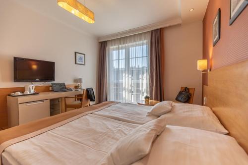 a hotel room with a large bed and a desk at City Hotel Miskolc in Miskolc
