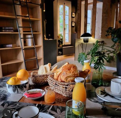 a table topped with baskets of bread and orange juice at Maison d'hôtes du Jardin in Saint-Valery-sur-Somme