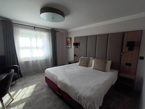 a hotel room with a large bed and a window at Corn Mill Lodge Hotel in Leeds