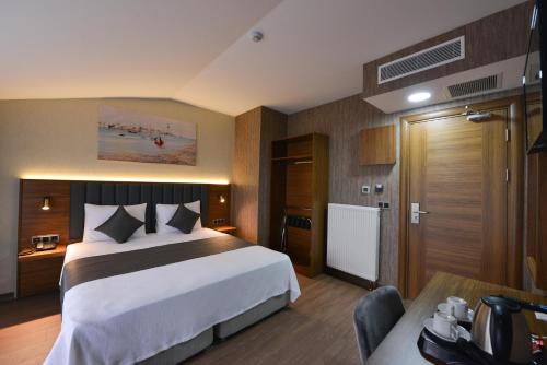 Cette chambre comprend un grand lit et un bureau. dans l'établissement İSTPORT GARDEN HOTELS, à Arnavutköy