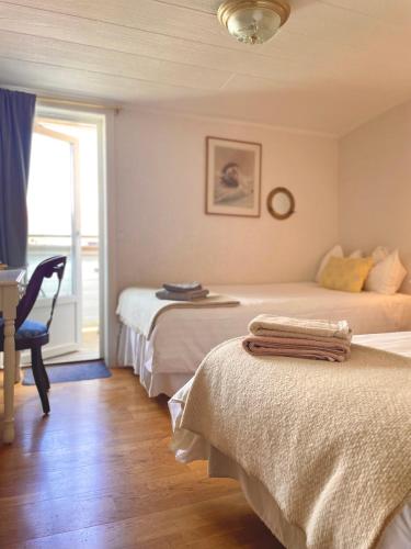 a bedroom with two beds and a desk and a window at Hotell & Restaurant Solliden in Stenungsund