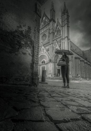 a person holding an umbrella in front of a church at Casa Dolce Casa in Orvieto