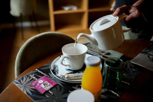 a person is pouring coffee into a cup on a table at Maison d'hôtes du Jardin in Saint-Valery-sur-Somme