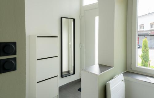 uma casa de banho com armários brancos e um espelho em Le Coin Vert em Hettange-Grande