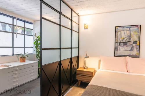 Schlafzimmer mit einem Bett und einer Glaswand in der Unterkunft Comfortable Apt. w/ Terrace & Lovely Lighting 101 in Mexiko-Stadt
