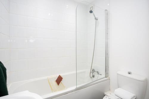 La salle de bains blanche est pourvue d'une douche et de toilettes. dans l'établissement Southend Serenity 2-Bedroom Flat - Southend Stays, à Southend-on-Sea