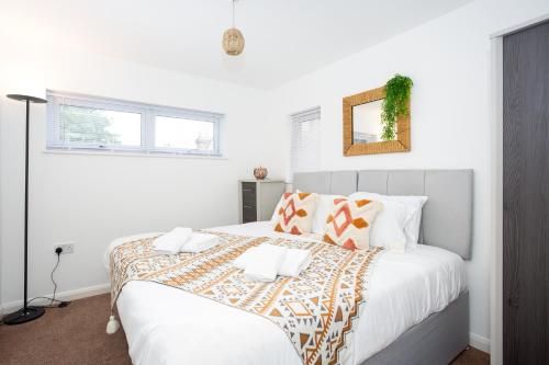 a white bedroom with a large bed with orange and white pillows at Southend Serenity 2-Bedroom Flat - Southend Stays in Southend-on-Sea