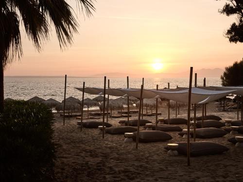 a beach with umbrellas in the sand and the ocean at The Bay Hotel & Suites in Vasilikos