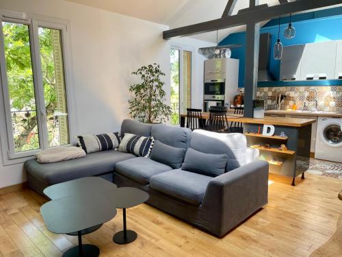 sala de estar con sofá azul y cocina en La Rive - Charmant logement bord de Marne en Champigny-sur-Marne