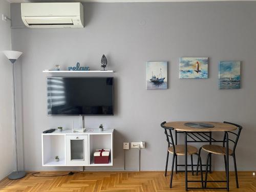 ein Wohnzimmer mit einem Tisch und einem TV an der Wand in der Unterkunft Apartman Kalina in Donje Mladice